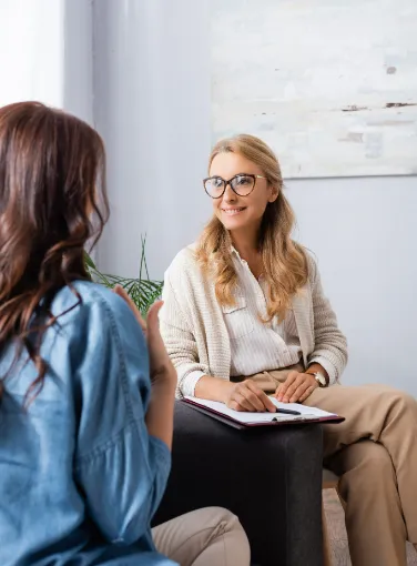 Two women sitting accross from each other and smiling