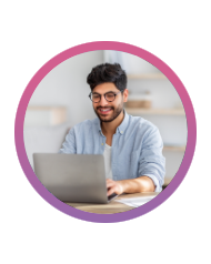 A man working on his laptop at a desk and smiling