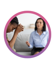 A woman sits with her head down, while another woman sits talking to her